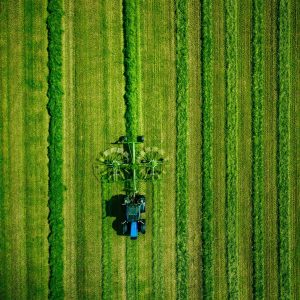 Aerial view of Tractor mowing green field in Finland.